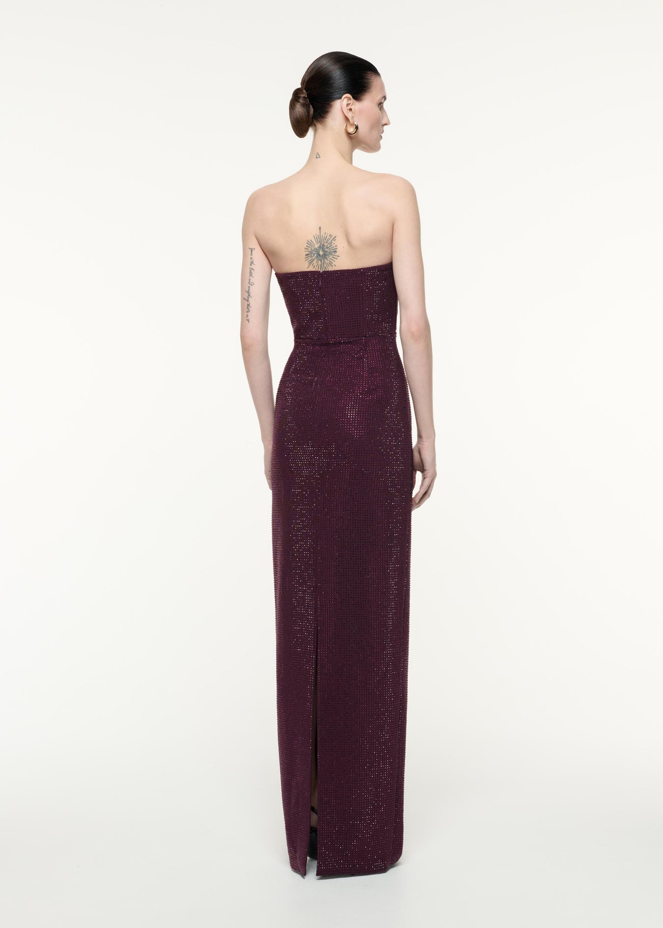 A back view image of a model wearing the Strapless Diamante Gown in Aubergine