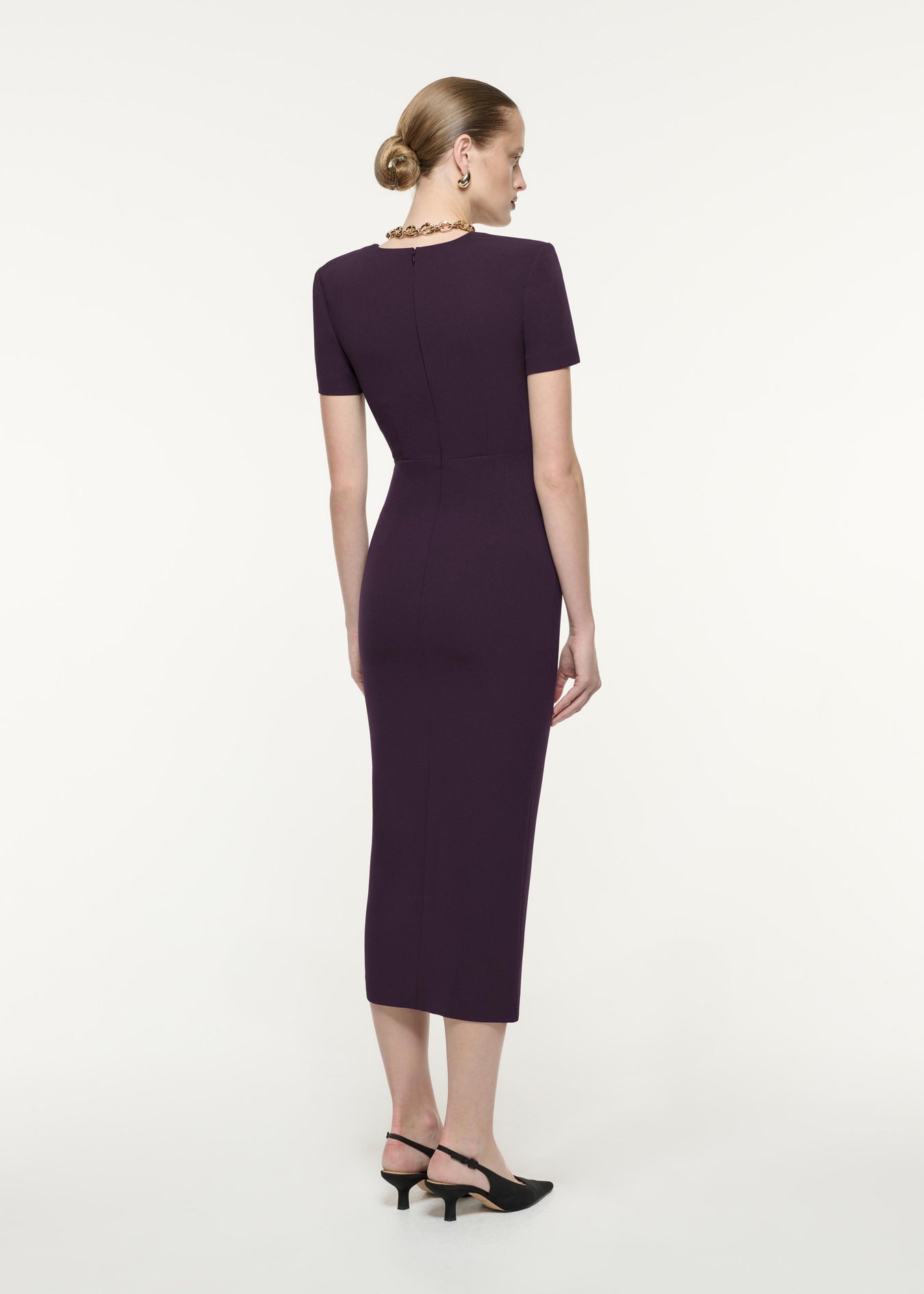 A back view image of a model wearing the Short Sleeve Heavy Cady Midi Dress in Aubergine