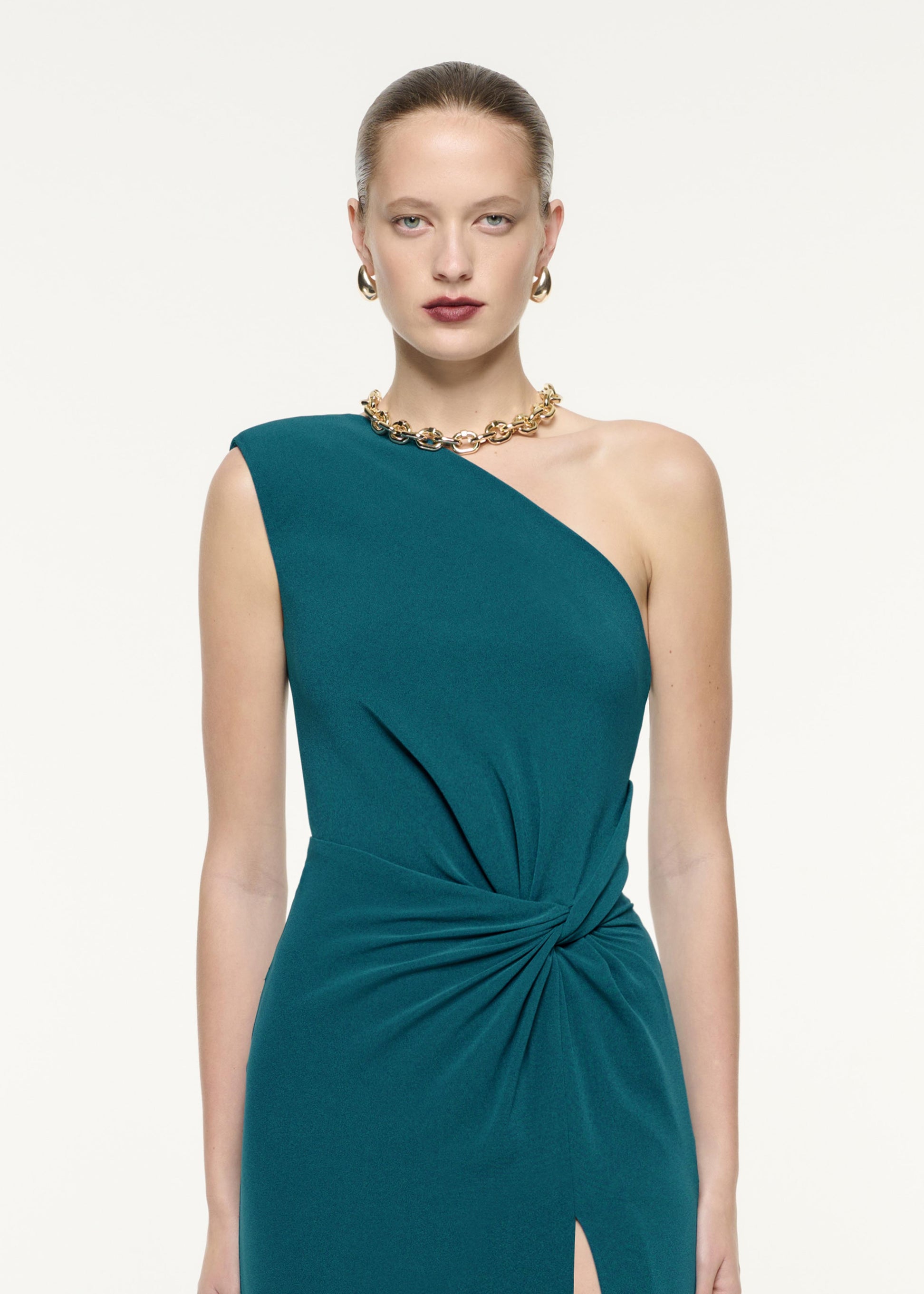 A close up image of a model wearing the Asymmetric Satin Crepe Maxi Dress in Green