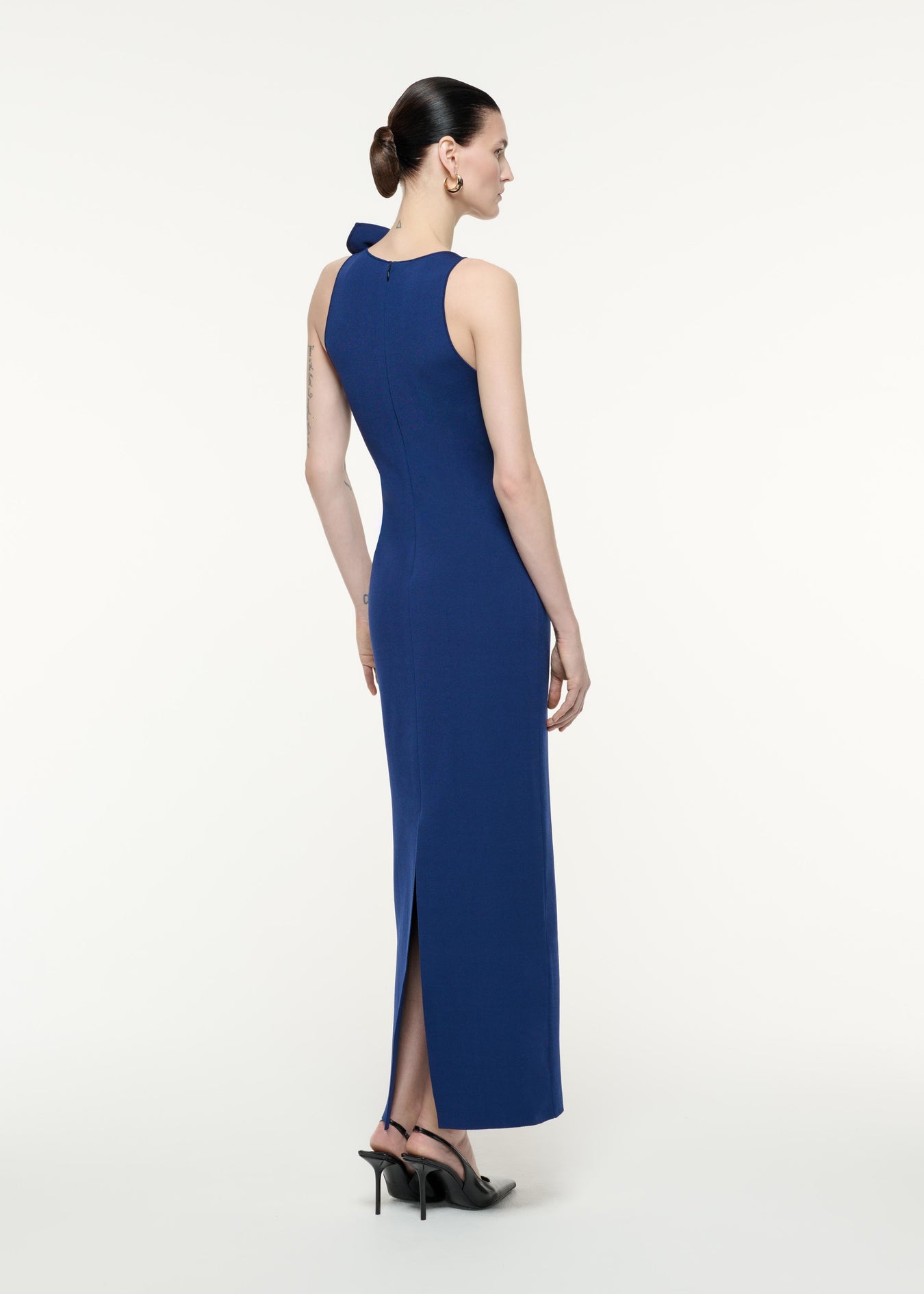 A back view image of a model wearing the Flat Knit Bow Max Dress in Navy