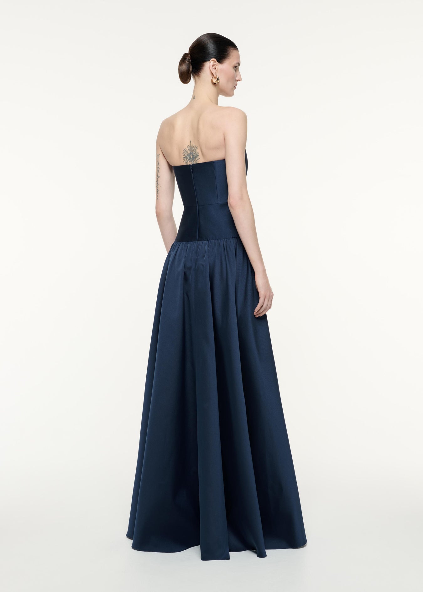 A back view image of a model wearing the Strapless Taffeta Gown in Navy