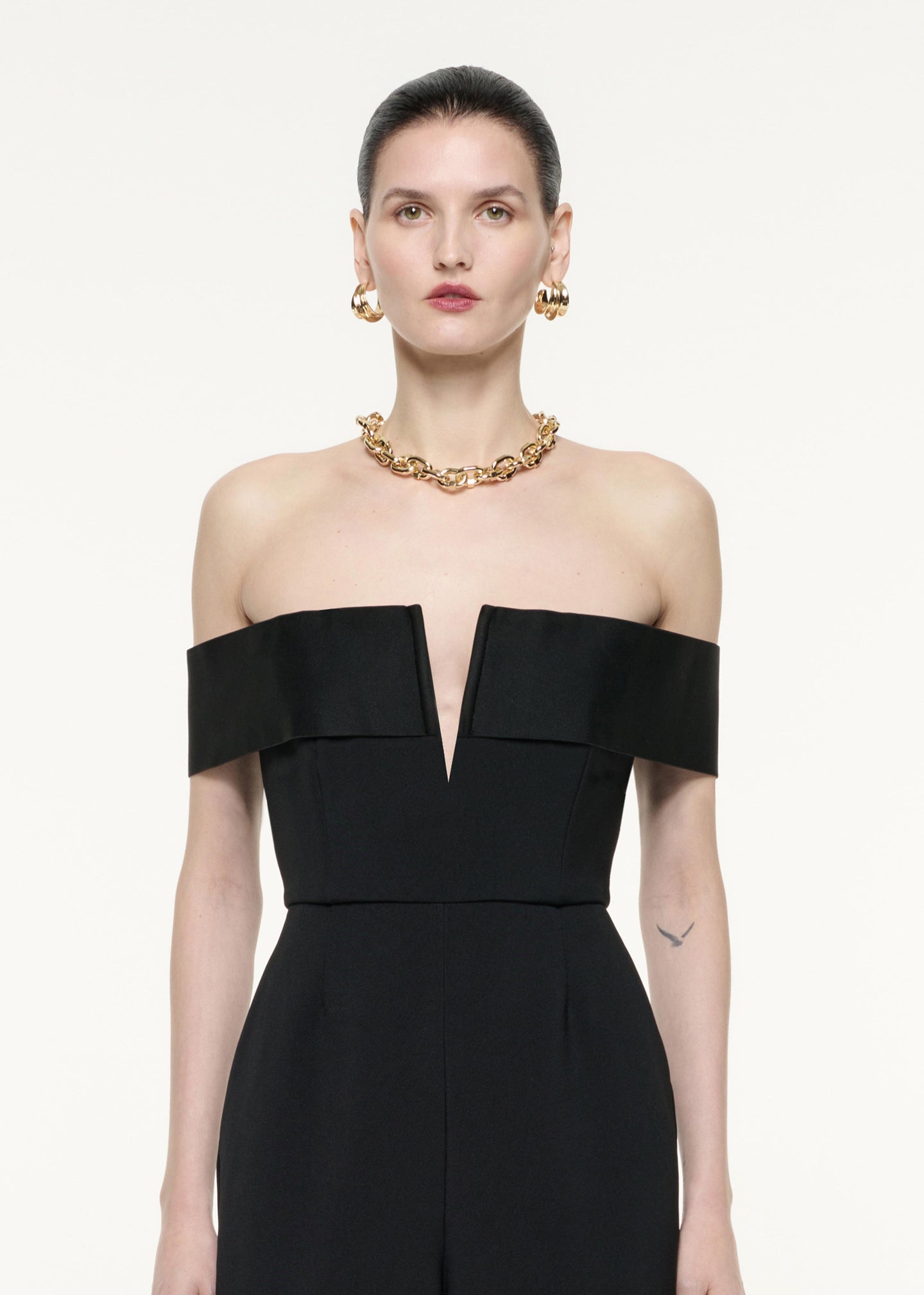 A close up image of a model wearing the Off The Shoulder Crepe Jumpsuit in Black