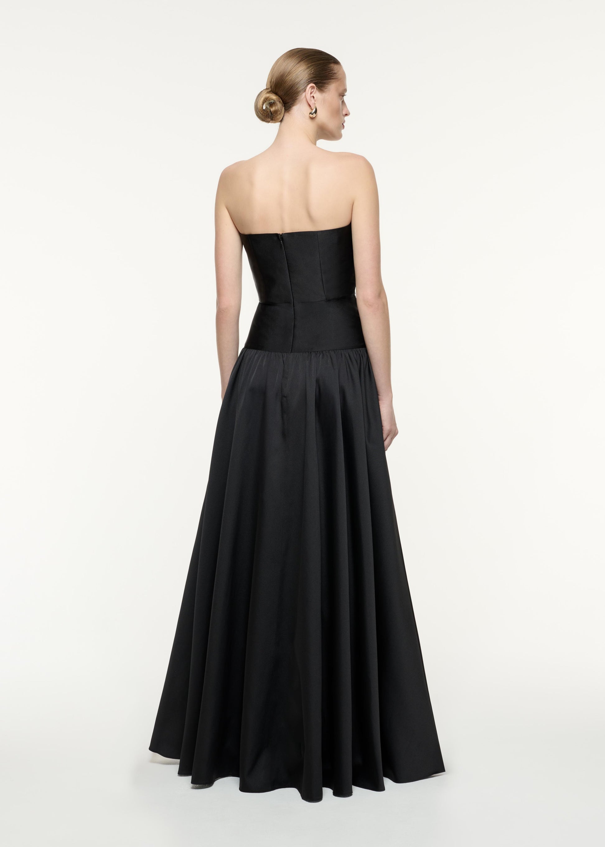 A back view image of a model wearing the Strapless Taffeta Gown in Black