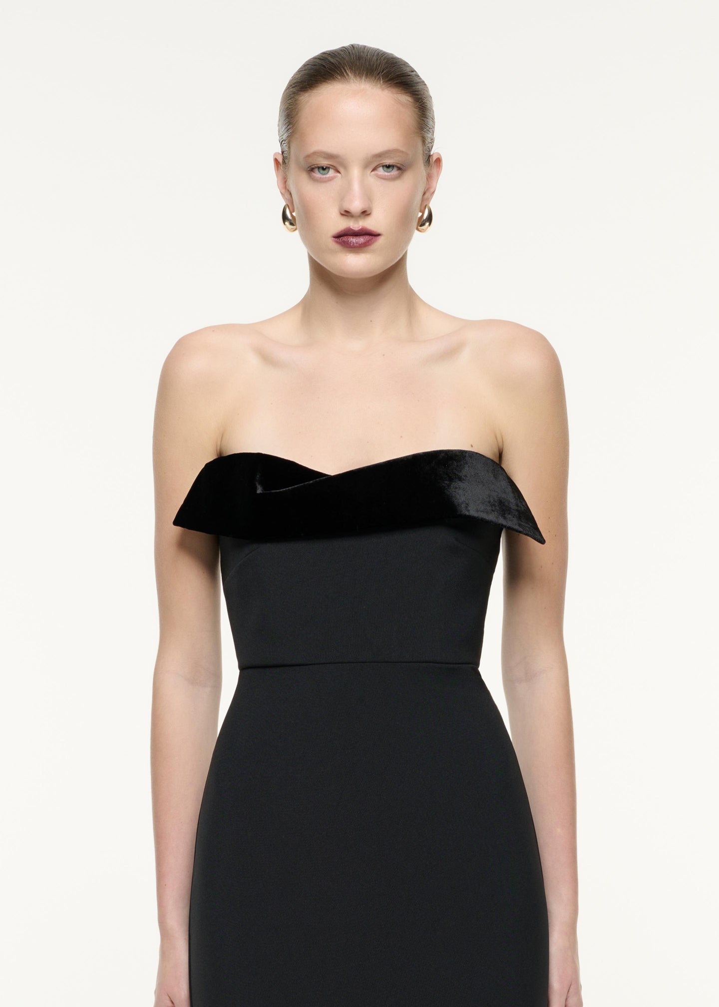 A close up image of a model wearing the Strapless Crepe Midi Dress in Black