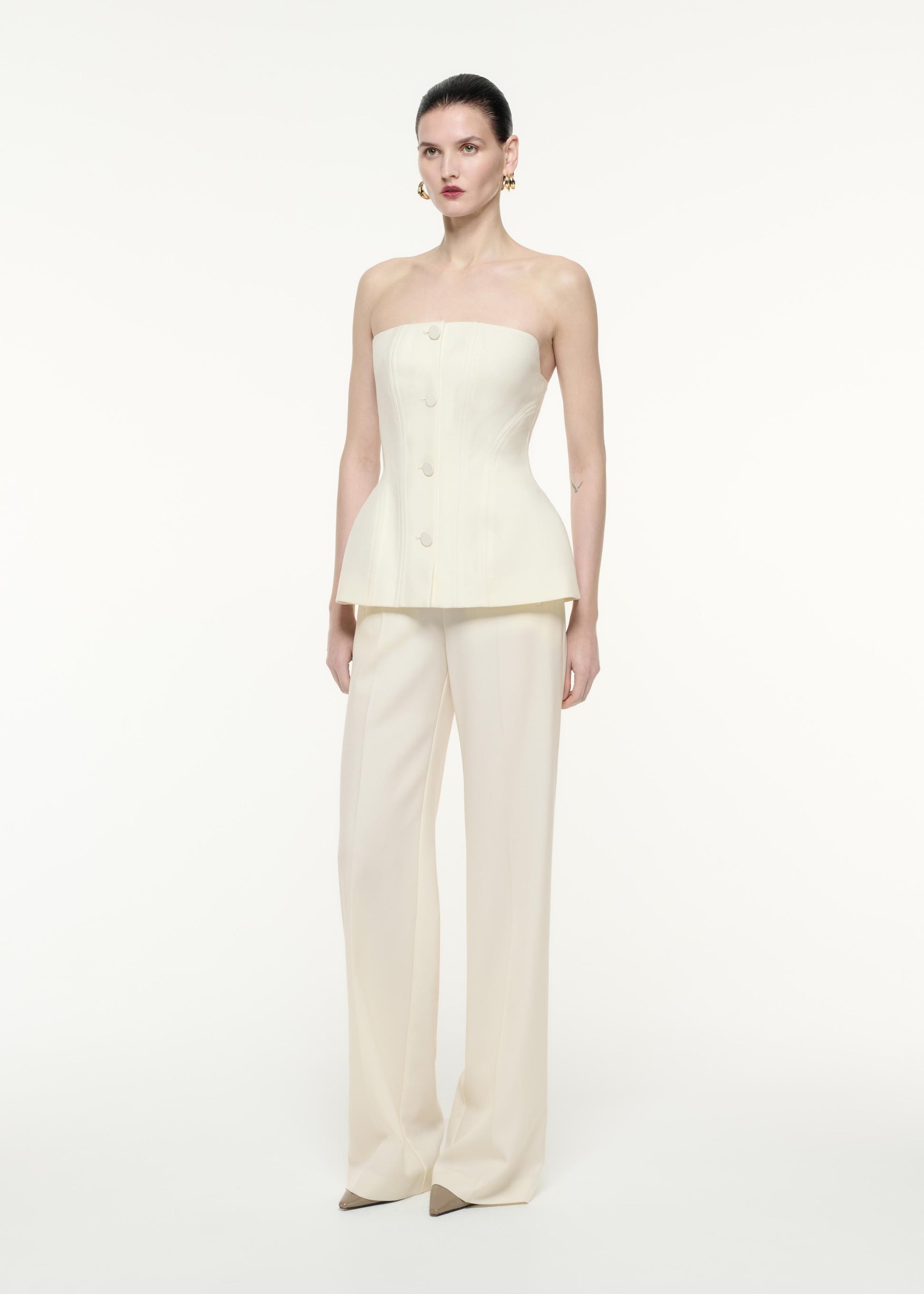 A side view image of a model wearing the Strapless Tailoring Wool Jumpsuit in Cream