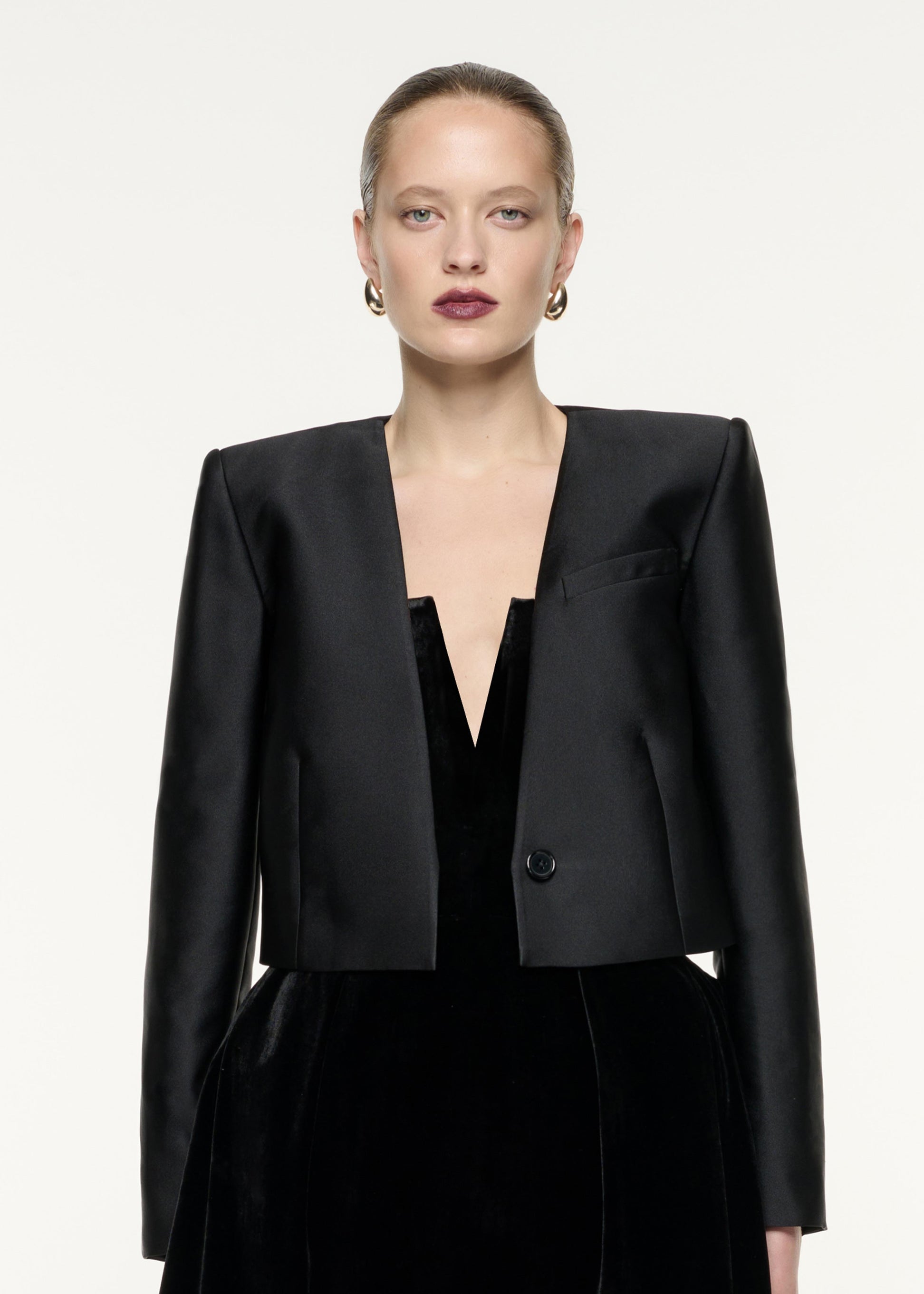 A close up image of a model wearing the Cropped Taffeta Jacket in Black