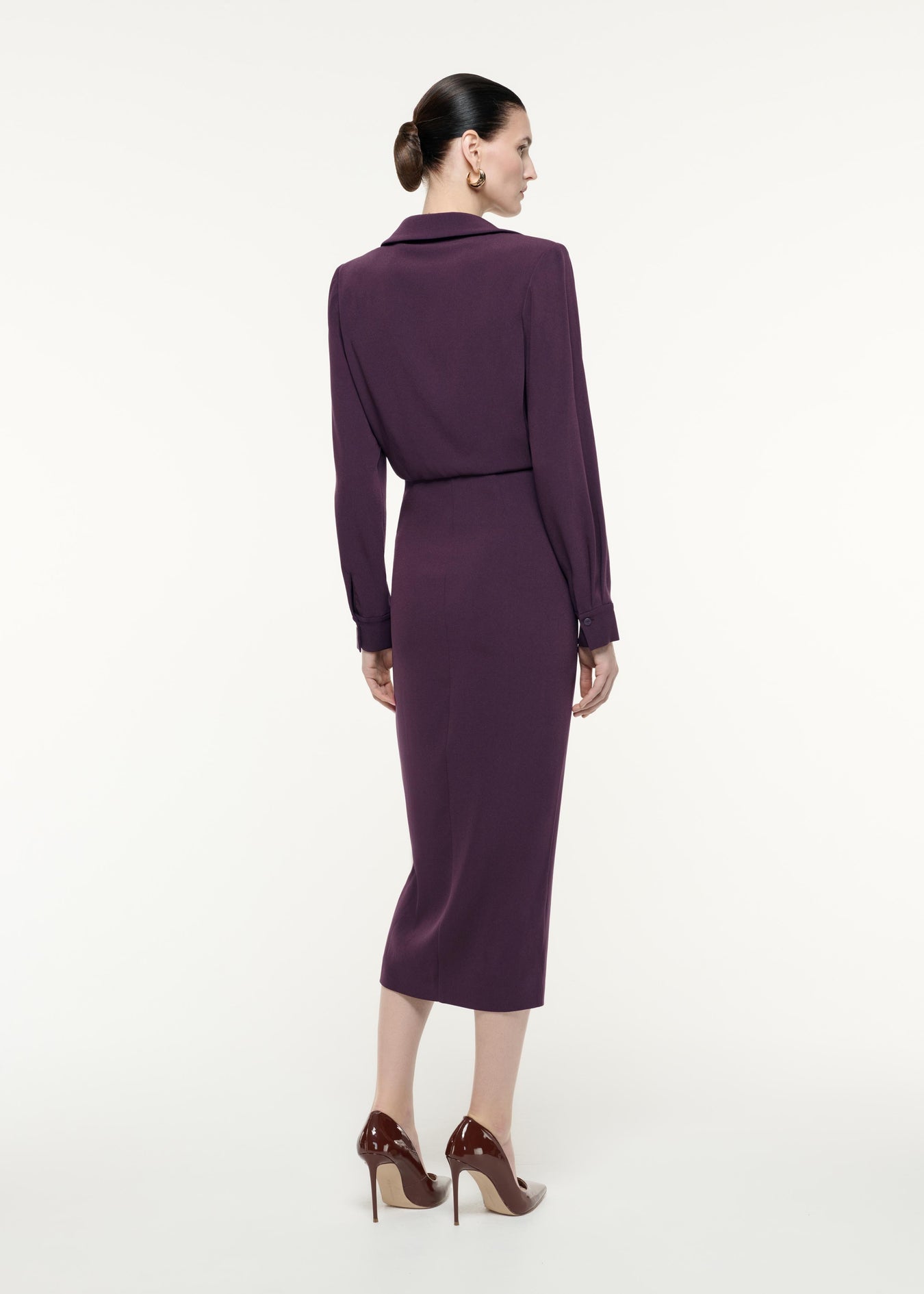 A back view image of a model wearing the Long Sleeve Satin Crepe Midi Dress in Aubergine