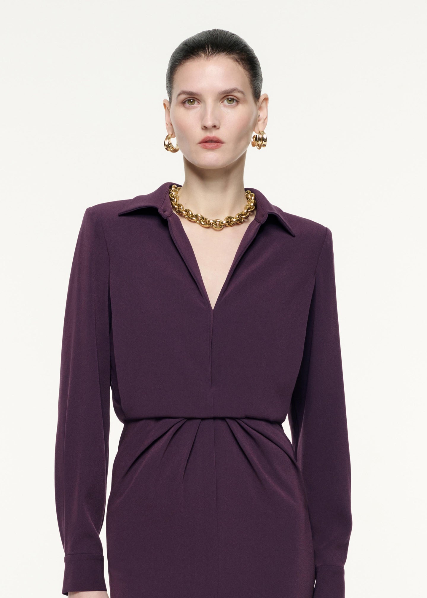 A close up image of a model wearing the Long Sleeve Satin Crepe Midi Dress in Aubergine