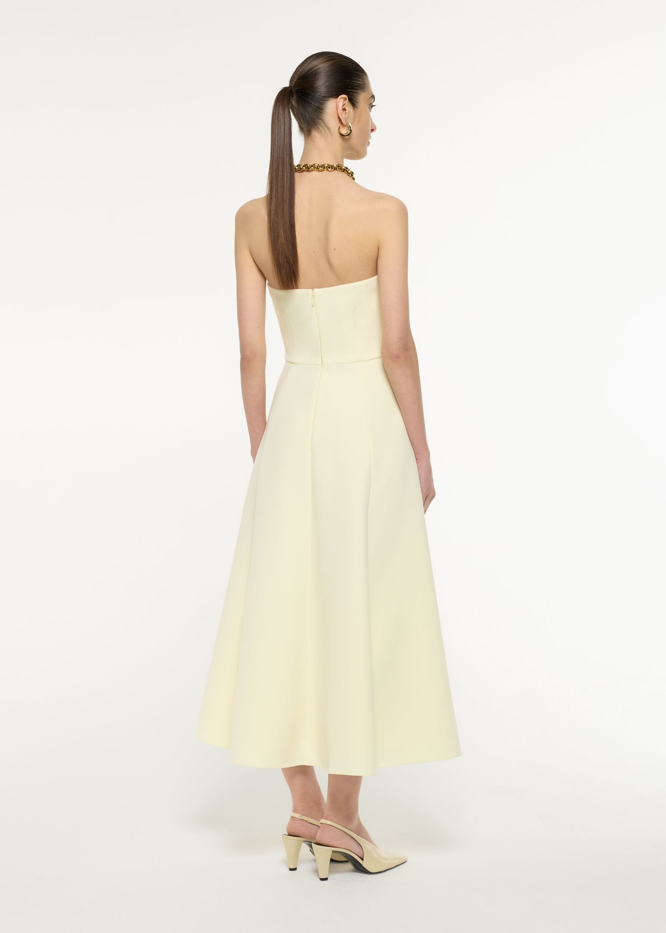 Back view of a model wearing the Strapless Drape Crepe Midi Dress in Light Yellow