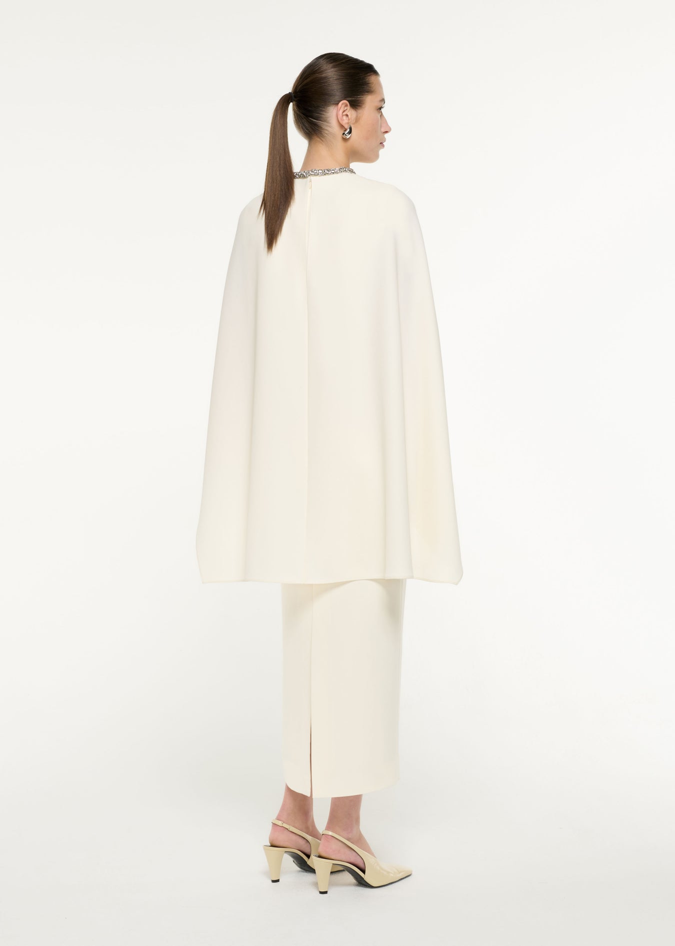 Back view of a model wearing the Heavy Cady Cape Midi Dress in Cream