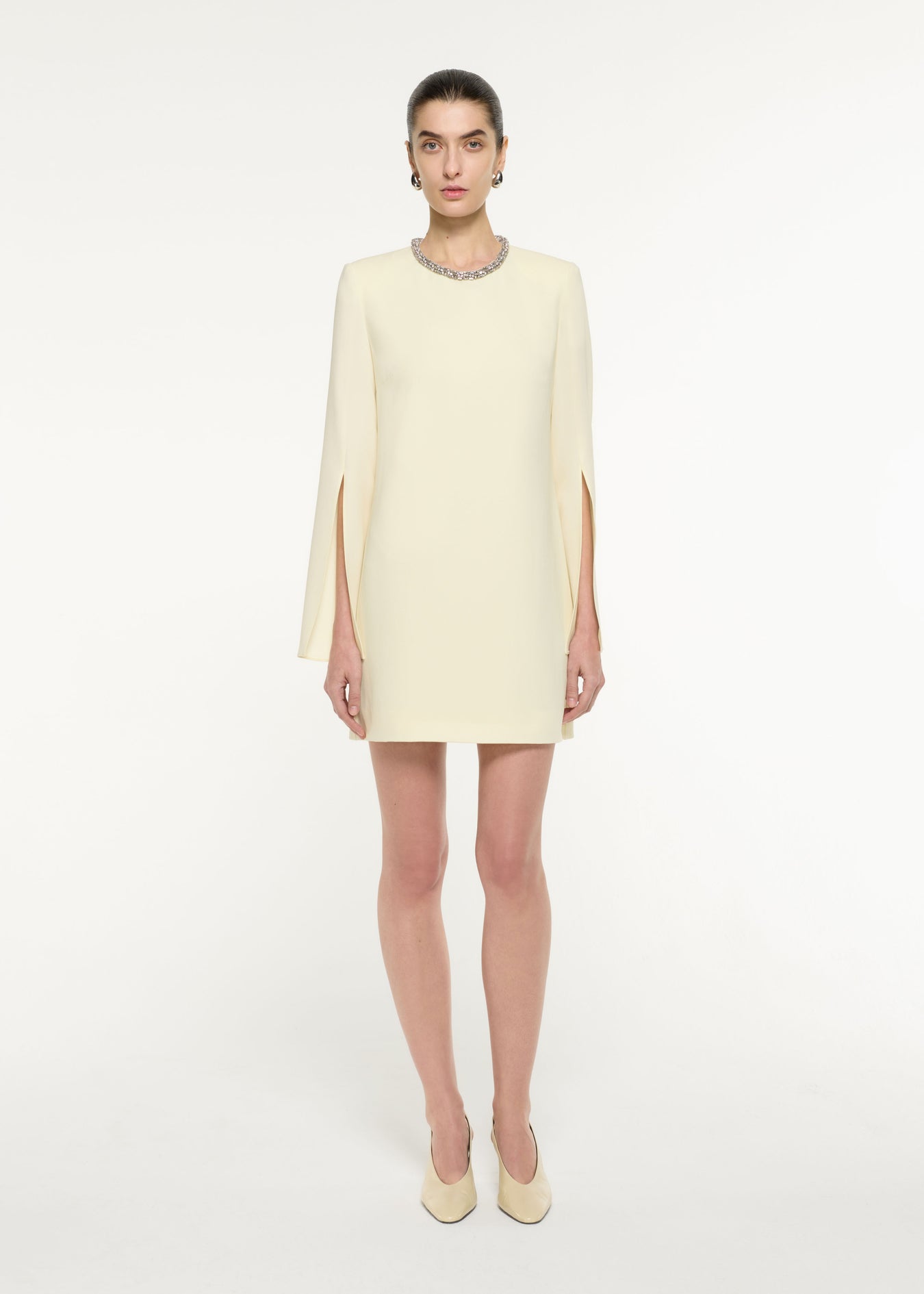 Front view of a model wearing the Cape Sleeve Embellished Mini Dress in Light Yellow