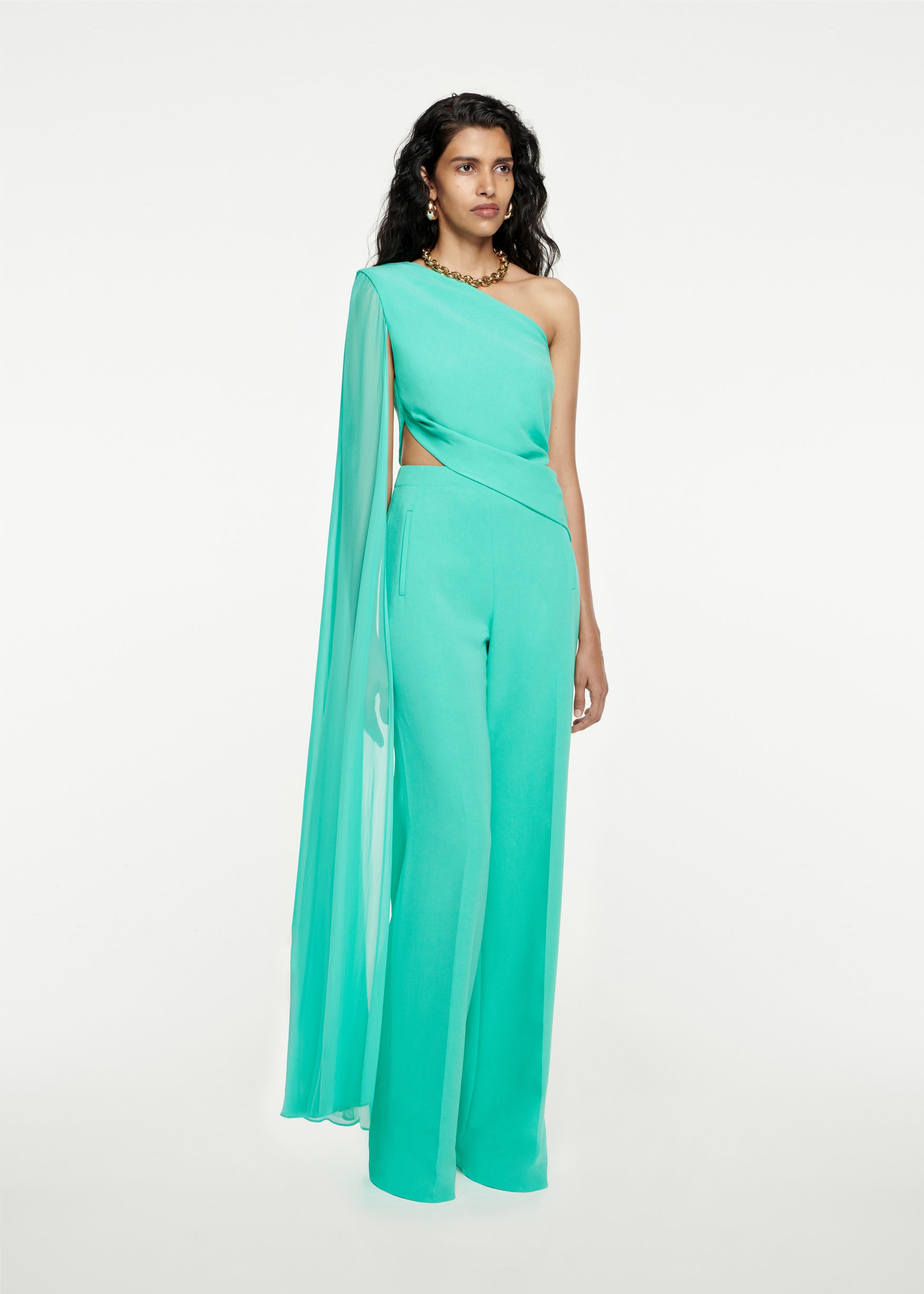 Woman wearing the Asymmetric Stretch-Cady Cape Jumpsuit in Turquoise